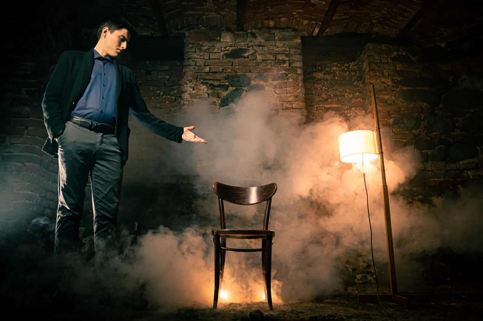 Rado Sheytanoff in a smoke-filled room, gesturing toward an empty chair lit by a single lamp